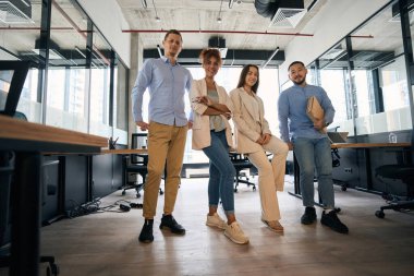 Photo of men and women in an office with panoramic windows. Coworking business