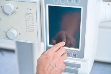 Mans hand adjusts the touch panel of an x-ray machine