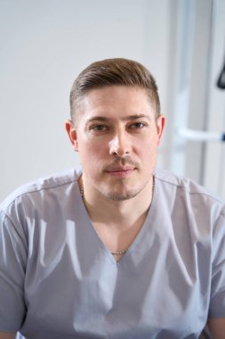 Portrait of a young handsome military doctor in medical clothes against the background of medical simulators