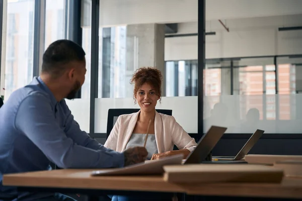 Company employee a male and female are talking and laughing while being in a large spacious office