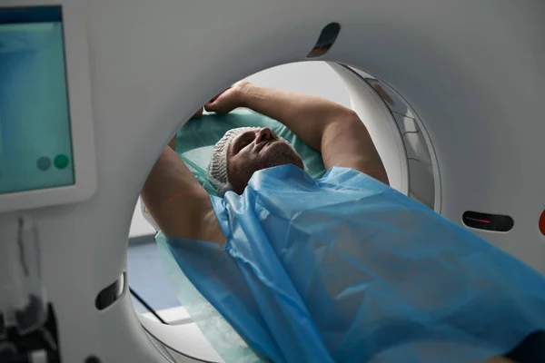 Patient with arms outstretched and eyes closed lies in the chamber of an efficient tomograph