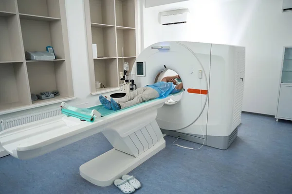 Patient in a modern medical center lies in a tomograph chamber on a diagnostic procedure.