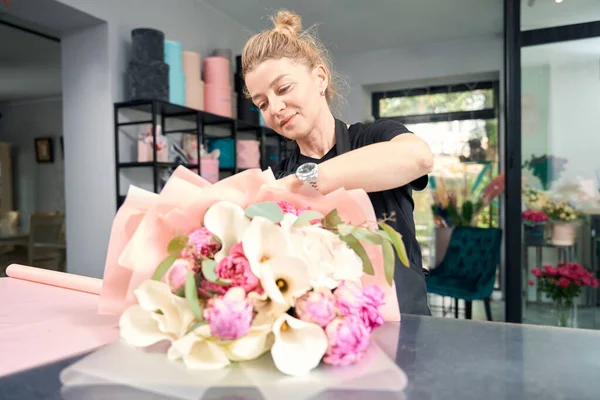 Portrait of cute female florist at work in flower shop. Creating chic fashionable flower bouquets