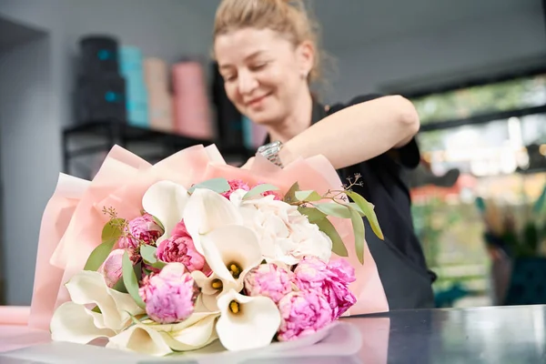Portrait of happy woman florist with ready bouquet in flower boutique. Creation of fashionable bouquets