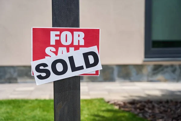 House sold plate sign, already sold on top, green grass background and cottage