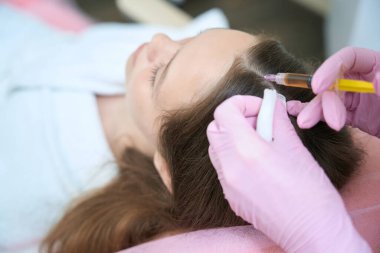 Close up of head injection process for better hair growth. Procedures in a beauty salon