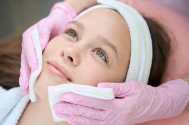 Tıbbi işlemden sonra yüzünü peçeteyle silen bir kızın portresi.