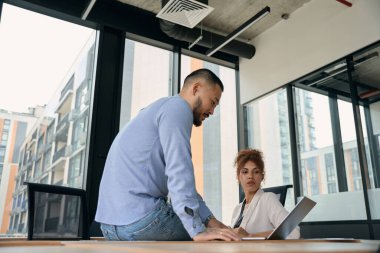 Ciddi genç iş kadını ve erkek arkadaşı bilgisayar ekranına bakıyor.