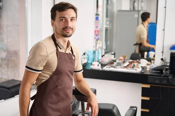 Vriendelijke Barbershop Werknemer Uniform Lachend Naast Kapsalon Stoelen Spiegel — Stockfoto