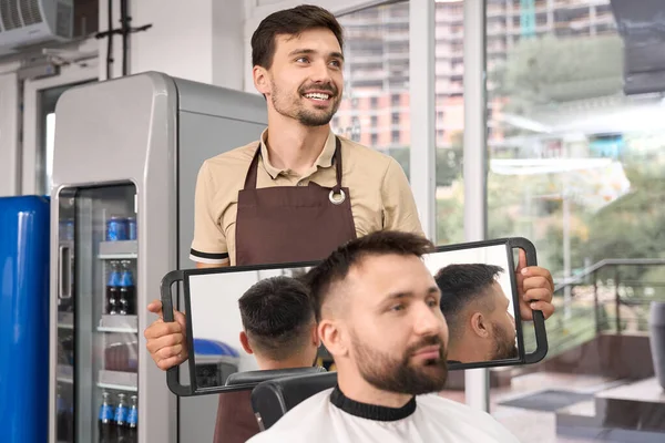 Gururlu Berber Katlanabilir Aynayı Tutarken Müşteriye Her Yandan Yeni Saç — Stok fotoğraf