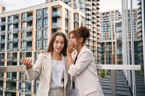 Business Lady Whispering Something Ear Her Young Pleased Female Colleague — Stock Photo, Image