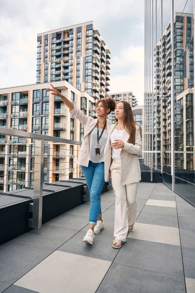 Fröhliche Büroangestellte Zeigt Ihrem Freund Beim Spaziergang Auf Balkon Stadtbild — Stockfoto