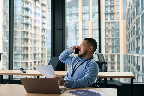 Businessperson Dokumentem Ruce Sedí Přenosném Počítači Během Telefonátu — Stock fotografie