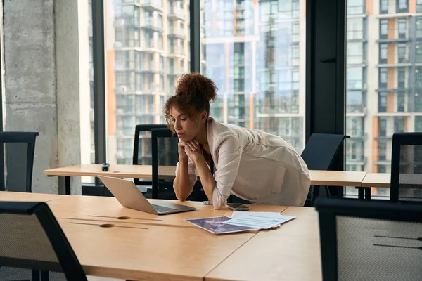 Ernsthaft Fokussierte Geschäftsfrau Lehnt Schreibtisch Und Blickt Auf Den Laptop — Stockfoto