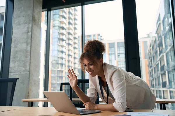 公司快乐的员工靠在笔记本电脑屏幕上 在视频通话中向某人挥手 — 图库照片