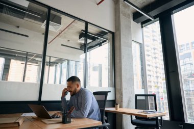 Gülümseyen neşeli ofis müdürü bilgisayarının başında oturmuş akıllı telefonuyla konuşuyor.