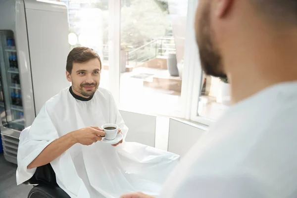 Satisfied Young Man Barbershop Chair Drinking Coffee Looking Gratefully His — Stock Photo, Image