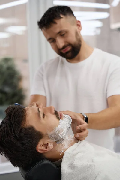 Bonito Cavalheiro Com Espuma Rosto Descansando Cadeira Barbearia Enquanto Está — Fotografia de Stock