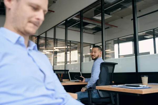 Uśmiechnięty Pracownik Biurowy Siedzi Laptopie Smartfonem Ręku Podczas Gdy Jego — Zdjęcie stockowe