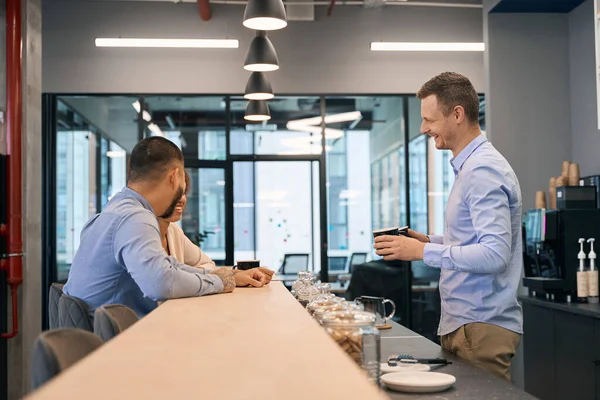 Vrolijke Jonge Bedrijfsmedewerker Communiceert Met Zijn Collega Die Aan Balie — Stockfoto