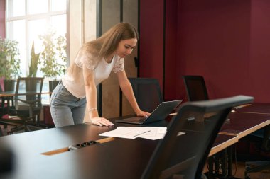 Laptop ekranına bakarken masaya yaslanan sakin bir şirket çalışanı.