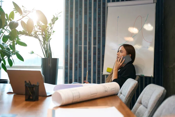 Joven Dibujante Seria Sentada Escritorio Con Dibujos Técnicos Durante Conversación — Foto de Stock