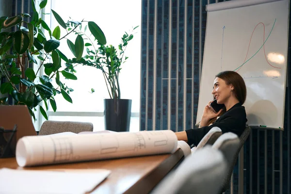 Nöjd Kvinnlig Arkitekt Sitter Vid Skrivbordet Smartphone Konversation Sitt Kontor — Stockfoto
