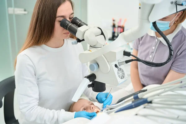 Konzentrierter Kinderzahnarzt Untersucht Mundhöhle Eines Frühgeborenen Mädchens Unter Dem Mikroskop — Stockfoto