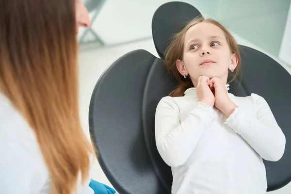 怖がっている若い患者は椅子に座って小児歯科医を見て — ストック写真