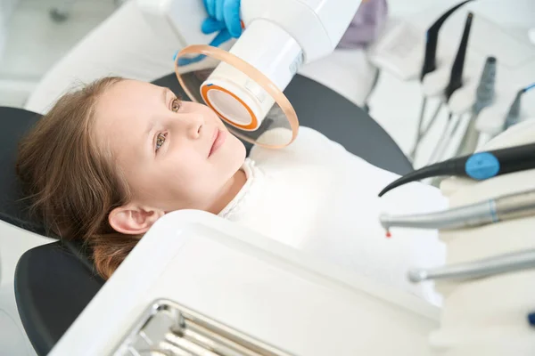 小さな女の子は 専門の小児歯科医によって行わ超低レベルレーザー療法中に歯科椅子に横たわっています — ストック写真