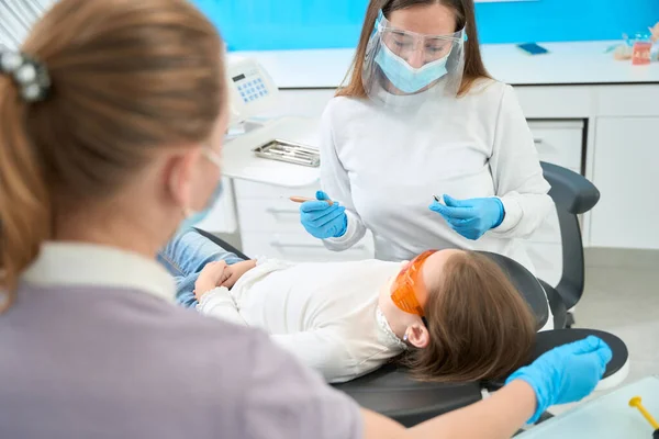 Pedodontist Met Tandheelkundige Instrumenten Haar Handen Kijken Naar Meisje Liggend — Stockfoto