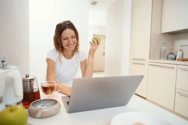 Mosolygó Hölgy Megoldja Munkahelyi Problémákat Online Miközben Egy Zöld Almát — Stock Fotó