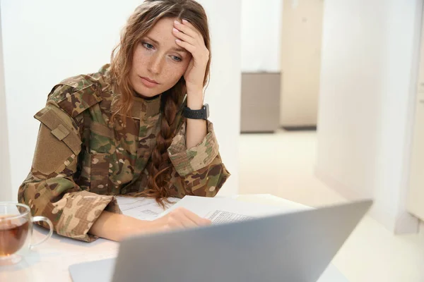 Frustrierte Dame Blickt Auf Laptop Bildschirm Während Arbeitspapiere Vor Ihr — Stockfoto