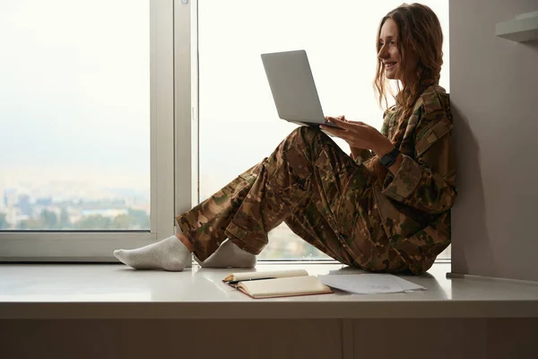 Happy Lady Military Sits Window While Holding Laptop Her Knees — Stock Photo, Image
