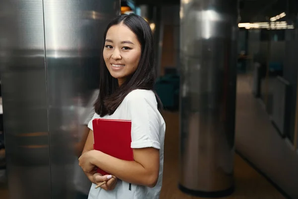 Side view portrait of beautiful stylish business lady is looking and posing at the photo camera in open space bright office