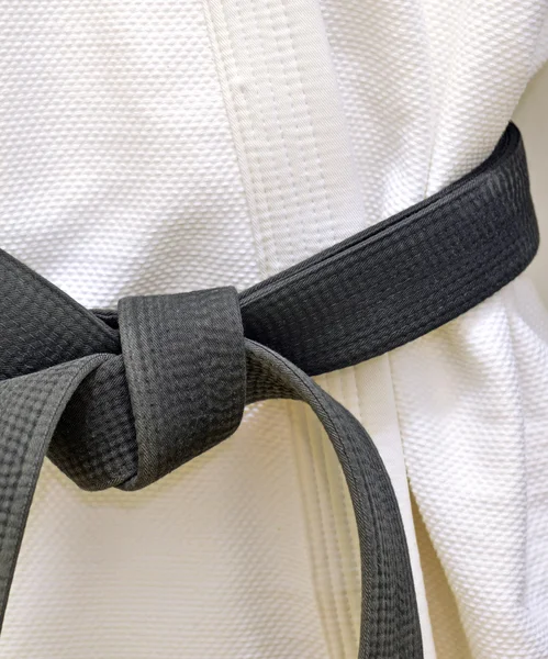 Karate schwarzer Gürtel auf weißer Uniform — Stockfoto
