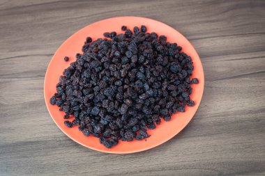 Kurutulmuş siyah kuru üzüm. Kuru üzümler kuruyan taze üzümlerle elde edilir. Kurutulmuş meyve grubuna dahil edilerek, eşlik edilmeden pişirilen veya yenilen en popüler gıdalardan biri haline getirilirler..