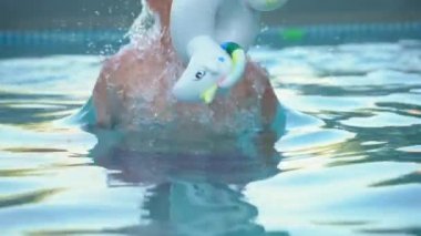 Küçük çocuk yüzme havuzunda yüzmeyi öğreniyor.