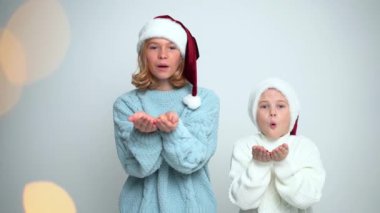 Noel Baba şapkalı genç kız ve oğlan konfeti üflüyorlar. Noel Konsepti