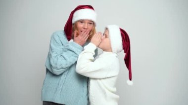 Mutlu genç kız ve çocuk Noel Baba şapkalı Fısıldıyor ve gülüyor