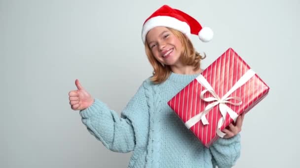 Szczęśliwa młoda dziewczyna w Santa Claus cap gospodarstwa obecny — Wideo stockowe