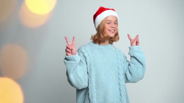 Jovem feliz em Papai Noel cap mostrar a paz pelos dedos — Vídeo de Stock