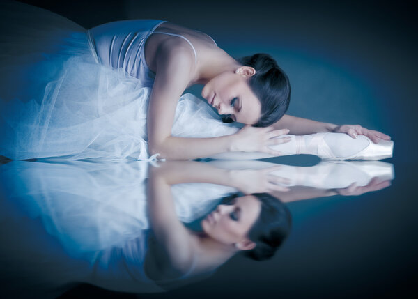 Lying ballerina with the reflection on the mirror