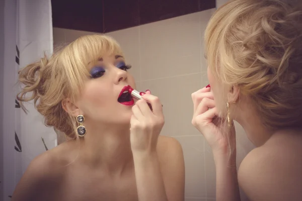 Woman putting red lipstick looking in mirror — Stock Photo, Image