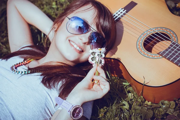 Chica con la guitarra tumbada en la hierba — Foto de Stock