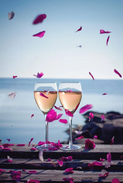 Copas de vino blanco con pétalos voladores —  Fotos de Stock