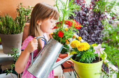 Adorable little girl watering flowers