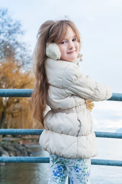 Cute little girl posing outdoors, standing next to lake with mountains — Stock Photo, Image