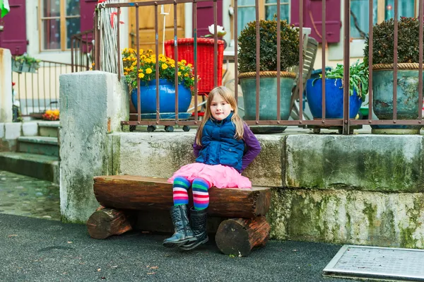 Porträtt av en söt liten flicka, klädd i blå jacka, rosa kjol och svarta stövlar — Stockfoto