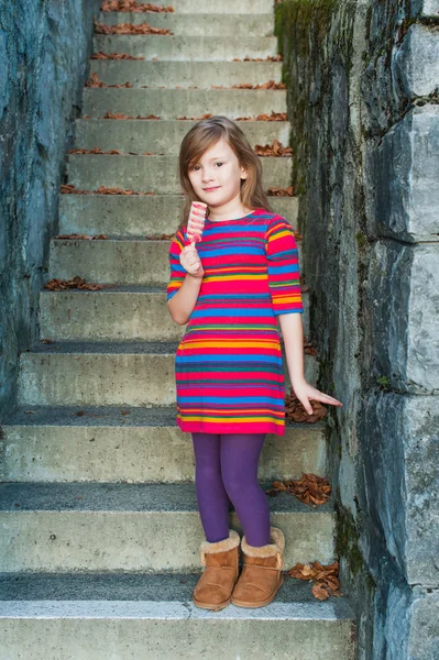 Renkli elbise adımlar üzerinde oturan güzel küçük kız — Stok fotoğraf